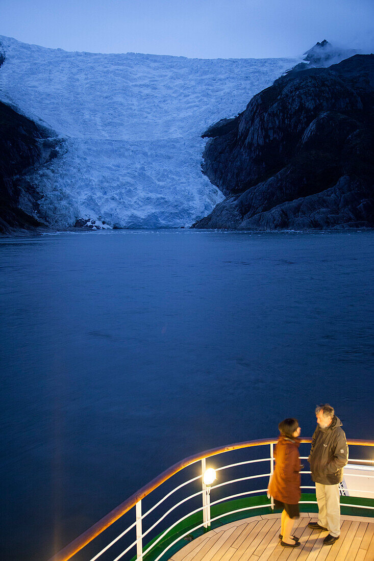 Paar an Deck von Kreuzfahrtschiff MS Deutschland, Reederei Peter Deilmann, vor dem Italienischen Gletscher im Dämmerlicht, Chilenische Fjorde, Magallanes y de la Antartica Chilena, Patagonien, Chile, Südamerika