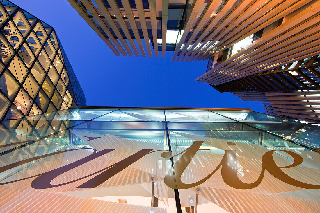 A wide-angle view at twilight captures the cluster of Designer Brand boutiques including Cartier and Omega at Minami-Aoyama Square with Prada next door in the upscale fashion district of Aoyama, located in central Tokyo, Japan.