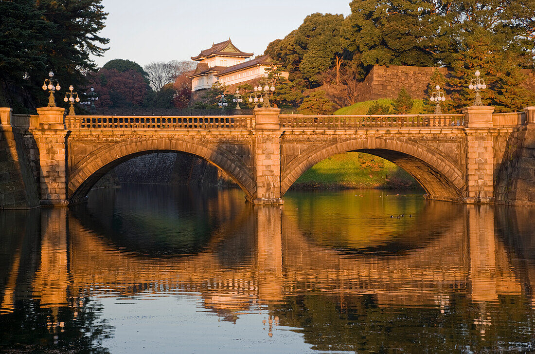 Dawn's first sunlight warmly illuminates Nijubashi Bridge and Fushimi Yagura Watchtower at the Imperial Palace in central Tokyo, Japan.