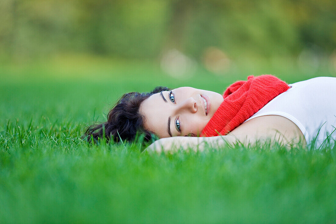 Beautiful woman lying down in park looking at camera