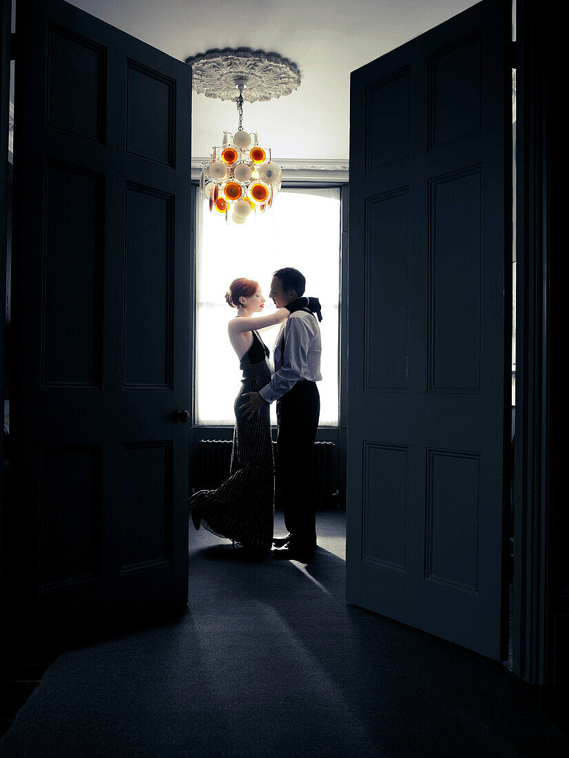 Young woman dancing with older man. Young woman dancing passionately with older man. Viewed through door opening.