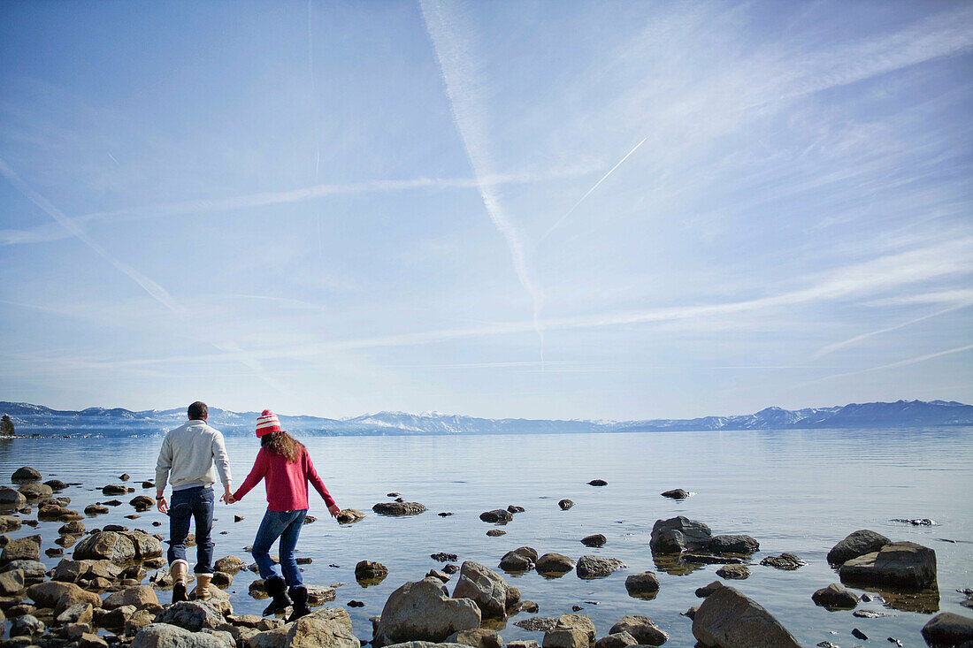 Couple walking on rocks near lake