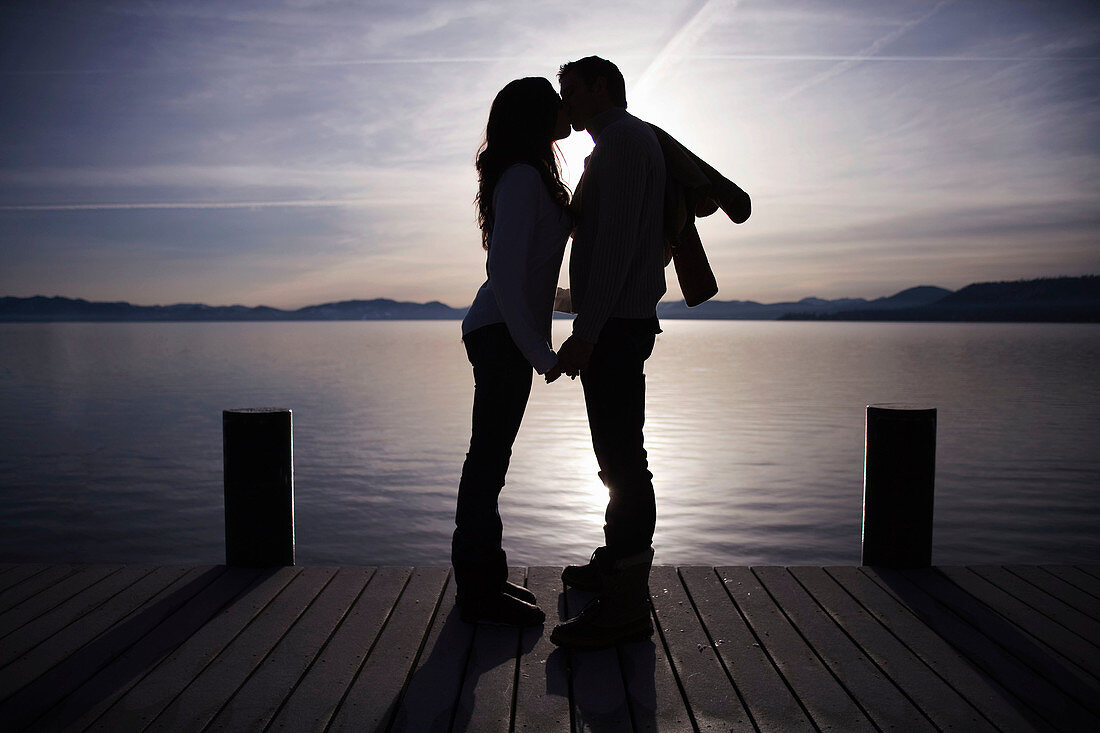 Couple kissing on pier at sunset
