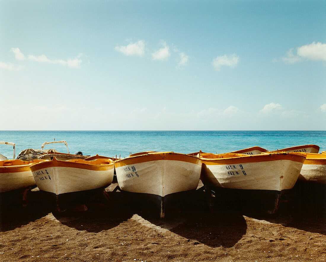 line of painted boats on beach. Wooden boats lined up on the beach at Positano, with sea behind