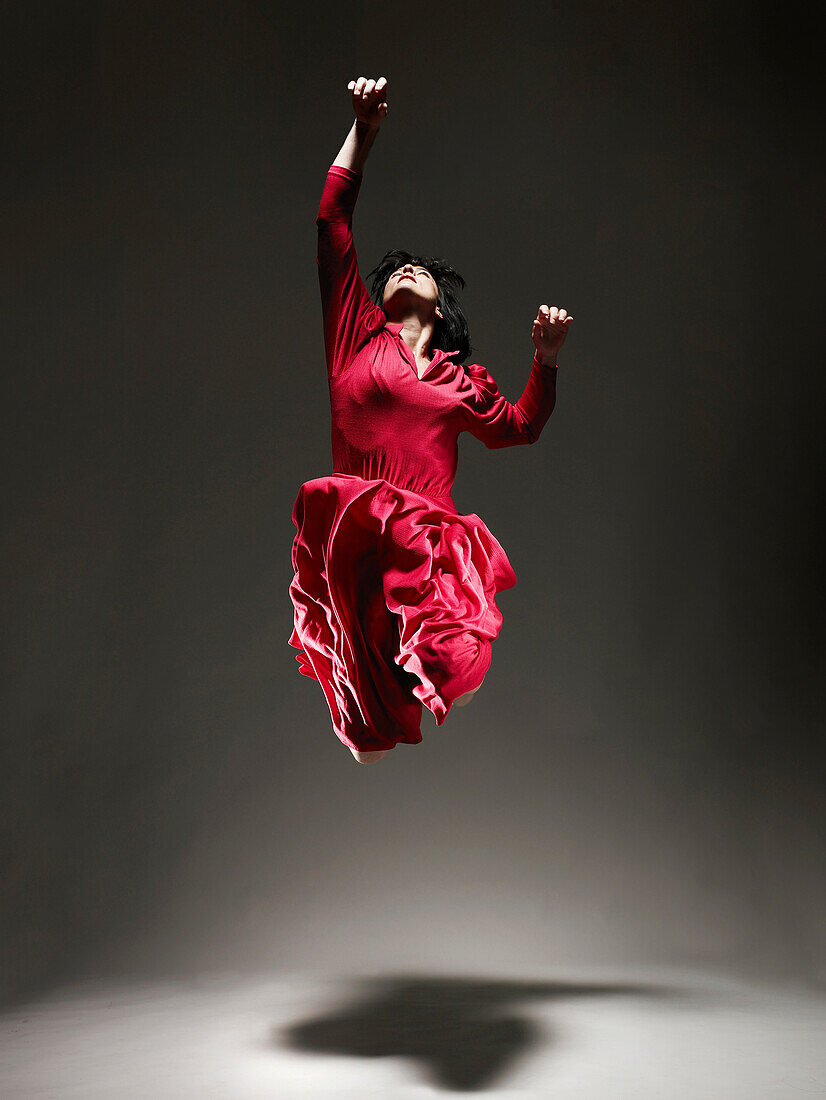 Frau in rotem Kleid tanzt unter Licht