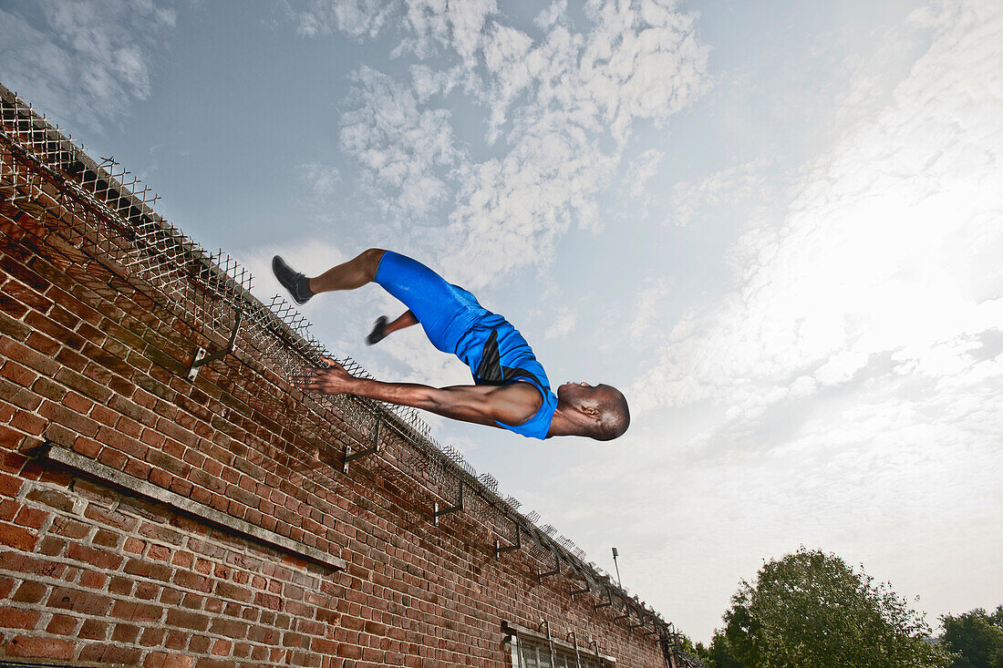 Athlete vaulting over brick wall. Athlete vaulting over brick wall
