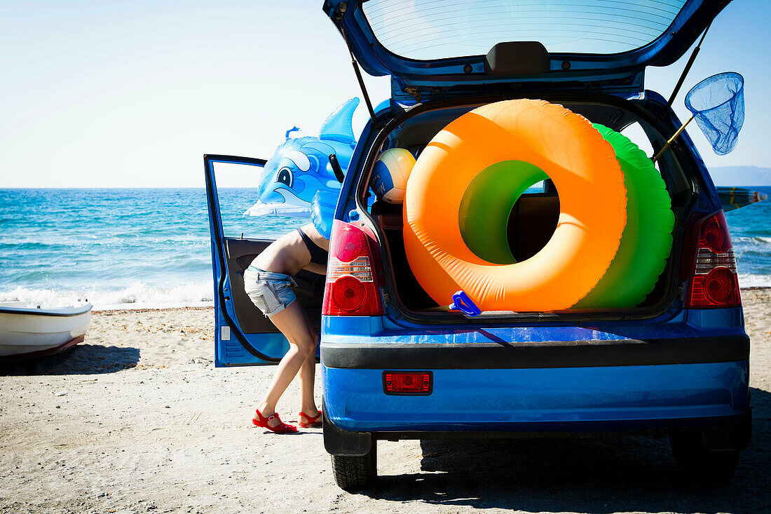 Woman unloading beach toys from car. Woman unloading beach toys from car