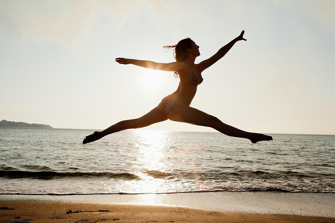 Woman leaping over waves on beach. Woman leaping over waves on beach