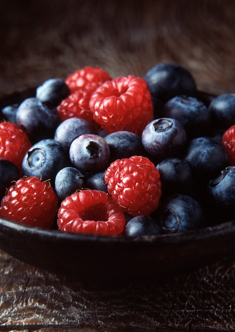 Bowl of blueberries and strawberries. Blueberries and Raspberries in wooden bowl