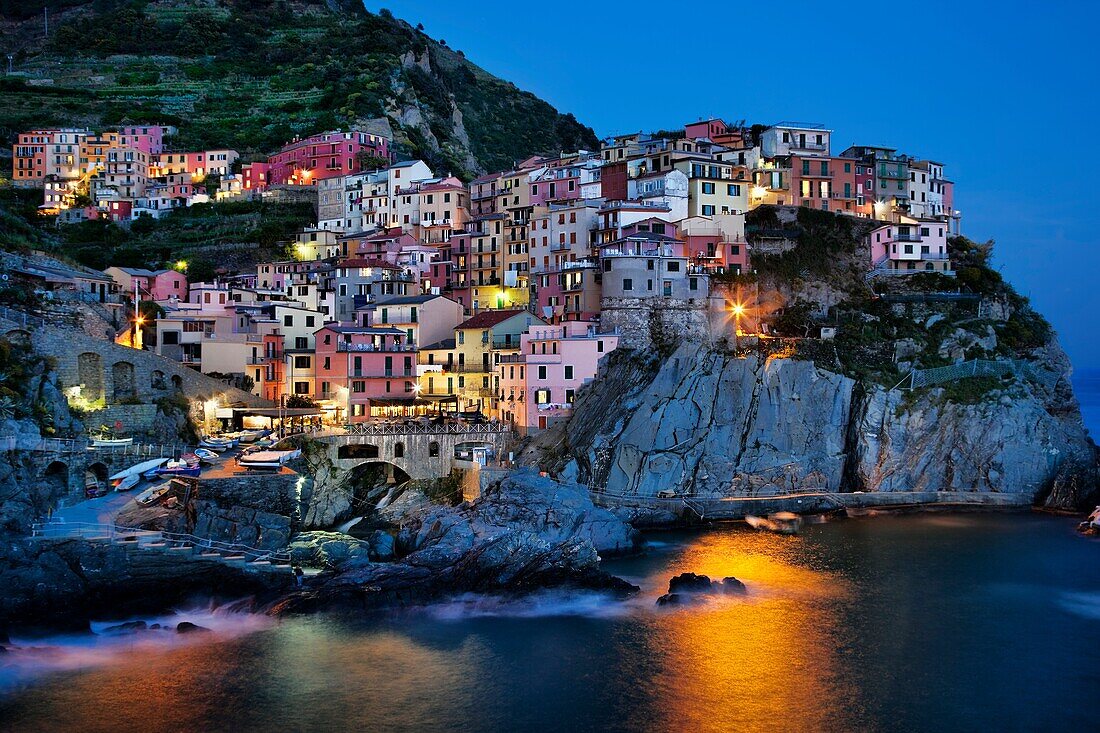 Manarola view at dusk across harbor with light reflection on water