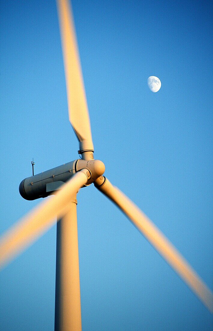 Wind turbine rotors with blue sky and moon generating electricity on wind farm at Bryn Titli near Rhayader, central Wales, UK