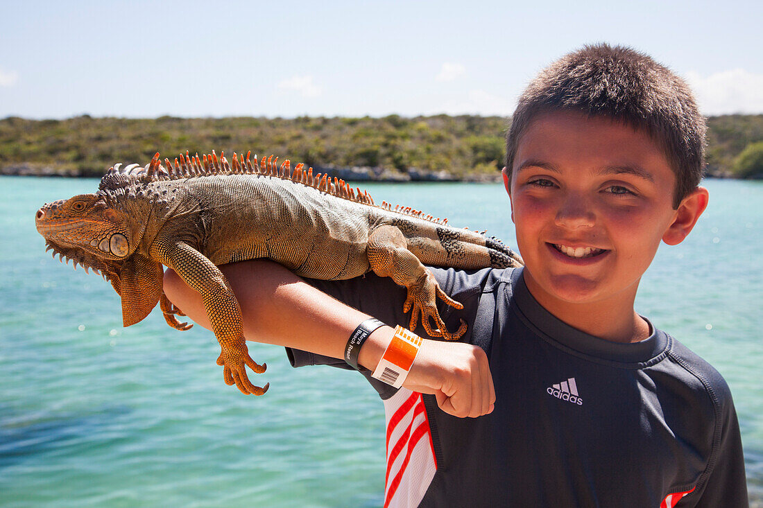 Ein Junge hält einen Leguan, Ctenosaura similis, auf dem Arm im Xel-Ha Park, Tulum, Riviera Maya, Quintana Roo, Mexiko, Mittelamerika