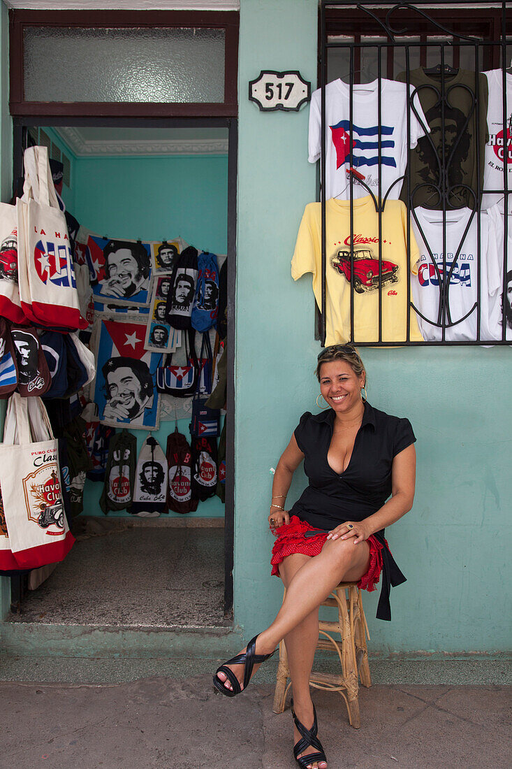 Eine Frau sitzt vor einem Geschäft mit Che Guevara Souvenirs, Havanna, Havana, Kuba, Karibik