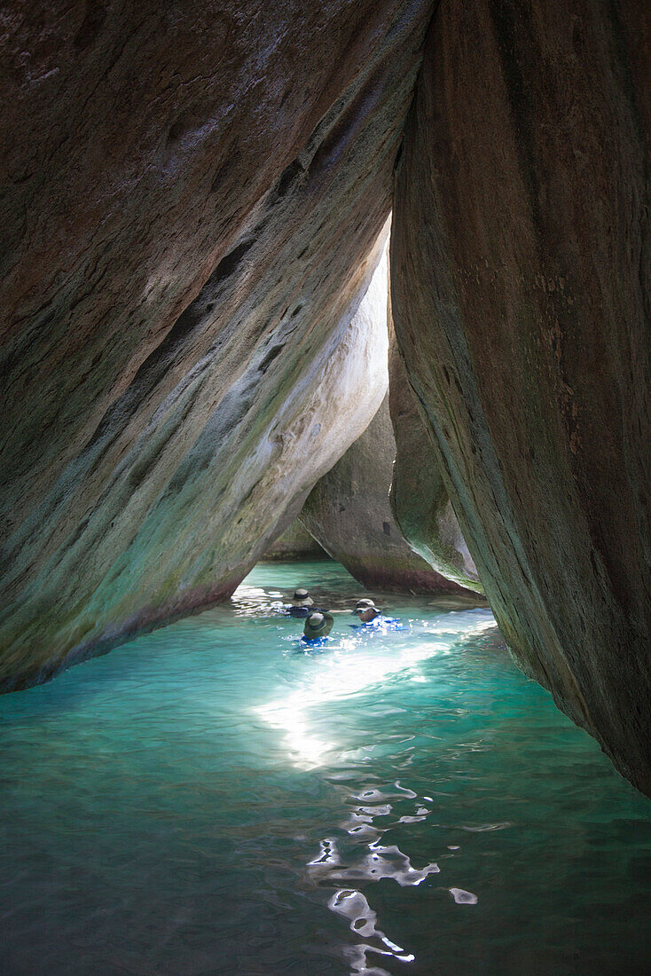 Menschen schwimmen inmitten riesiger Granitfelsen am Strand The Baths, Virgin Gorda, Virgin Gorda, Britische Jungferninseln, Karibik