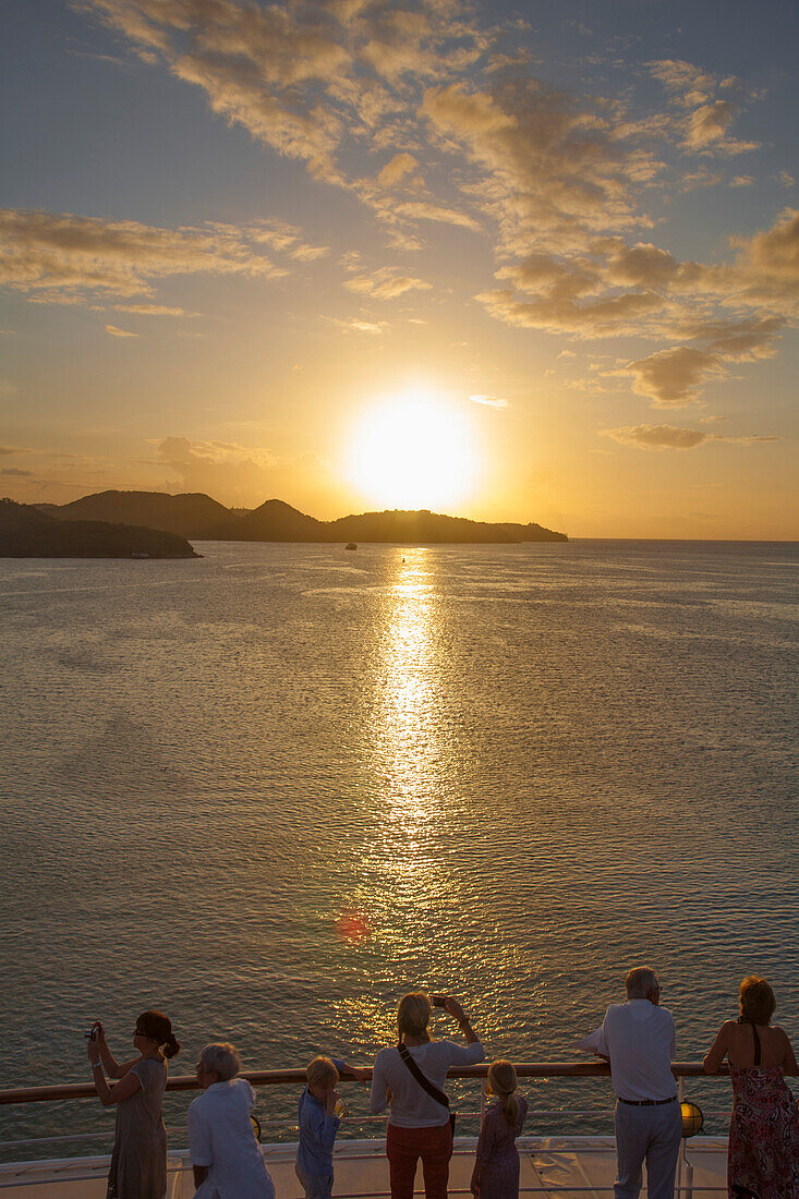 Menschen stehen an der Reling von Kreuzfahrtschiff MS Deutschland (Reederei Peter Deilmann) und blicken in den Sonnenuntergang, St. John, St. John, Antigua, Antigua und Barbuda, Karibik