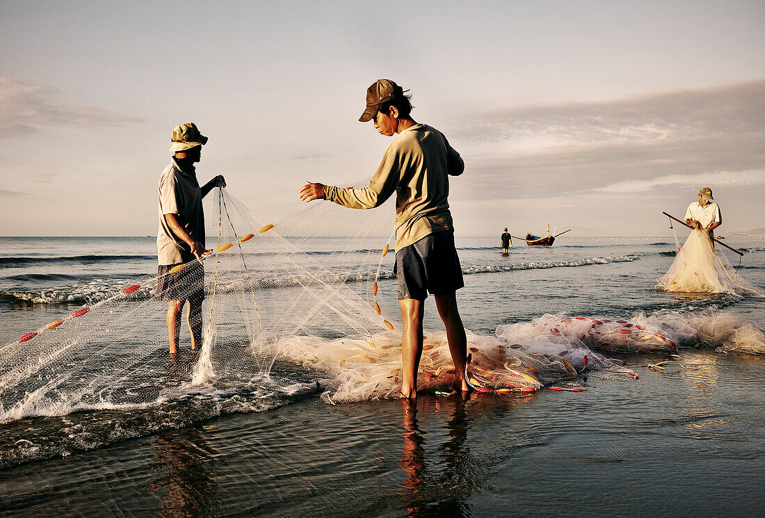 Fischer legen Netze am Strand zusammen nach getaner Arbeit, Fischerdorf Mui Ne, Vietnam, Südchinesisches Meer