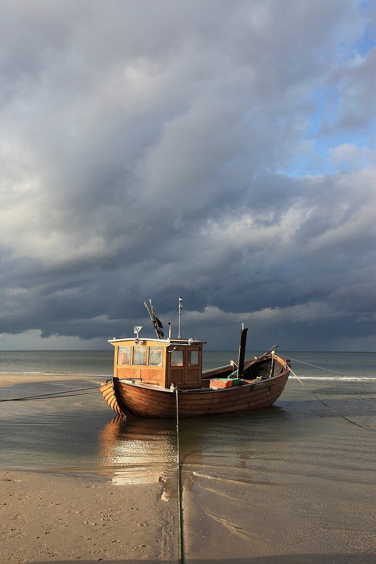 traditional wooden Fishing boat on the beach in the seaside resort of Ahlbeck in sunlight before thundershower, Usedom, Mecklenburg-Vorpommern, Germany, Europe