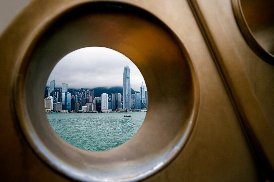 CHINA HONG KONG HONG KONG COASTLINE VICTORIA HARBOUR View of Hong Kong’s coastal frontline skyline shoot through a hole, part of a bronze sculpture at Kowloon’s side road called Avenue of Stars, shoot on a cloudy day