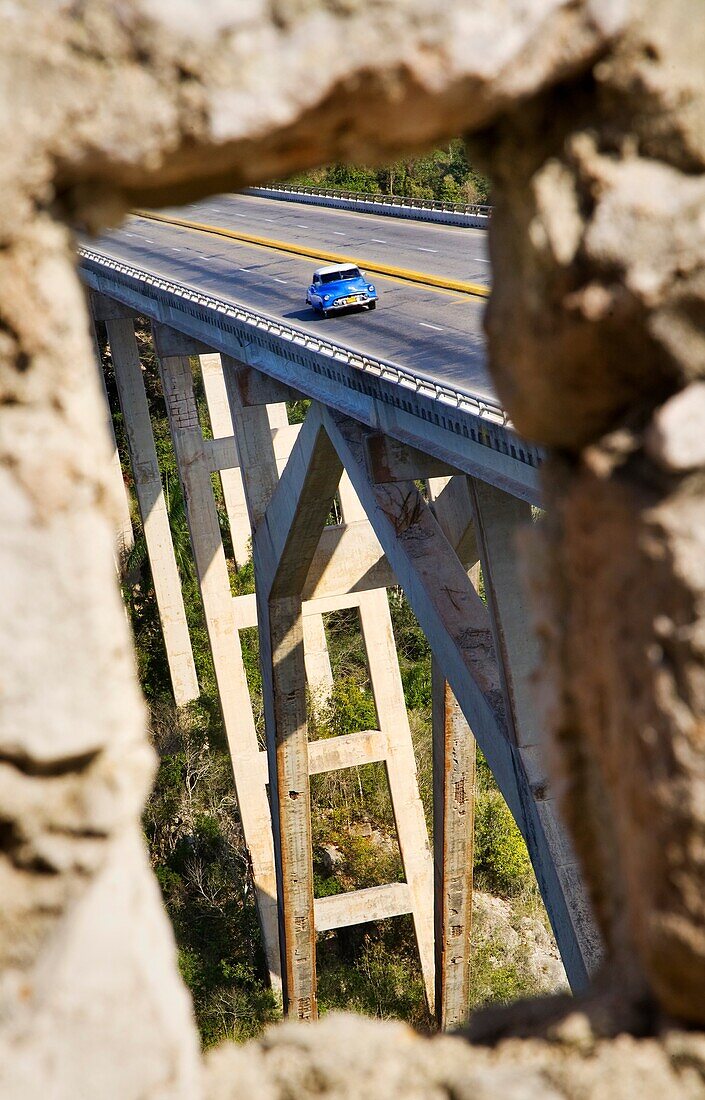 A blue vintage Cuban car crossing a bridge as it enters La Habana province in Cuba