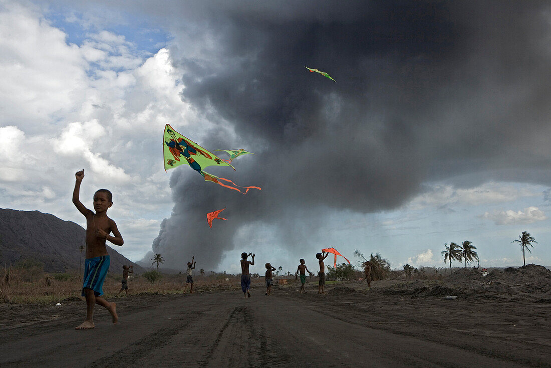 Kinder mit bunten Drachen im Vulkanasche, Tavurvur Vulkan, Rabaul, Ost-Neubritannien, Papua Neuguinea, Pazifik