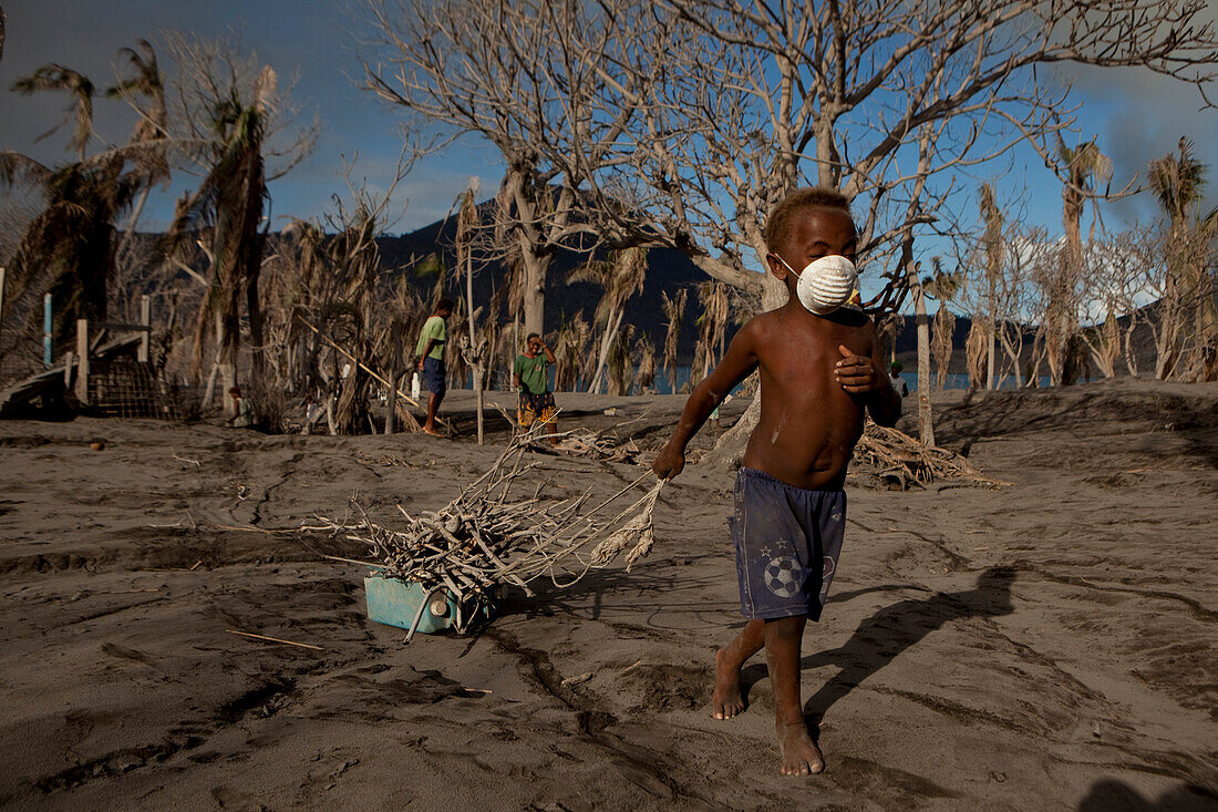 Kind bei der Suche nach Feuerholz. Eine Staubmaske ist sehr wertvoll, Tavurvur Vulkan, Rabaul, Ost-Neubritannien, Papua Neuguinea, Melanesien- Pazifik
