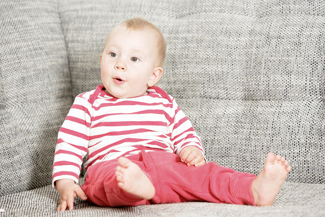 Baby sitzt auf einem Sofa, Wien, Österreich