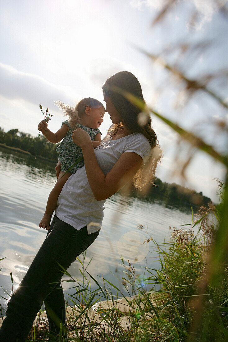 Young mother holding daughter at Danube riverbank, Old Danube, Vienna, Austria