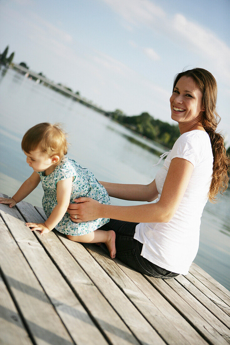 Junge Mutter und Tochter auf einem Holzsteg an der Donau, Alte Donau, Wien, Österreich