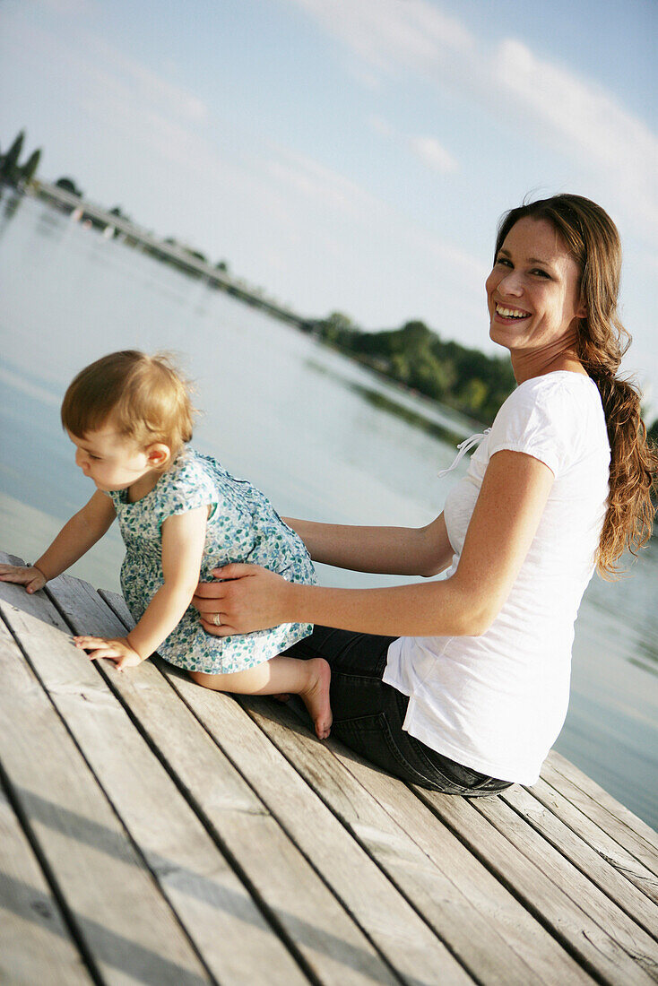 Young mother and daugther on wooden jetty at Danube river, Old Danube, Vienna, Austria