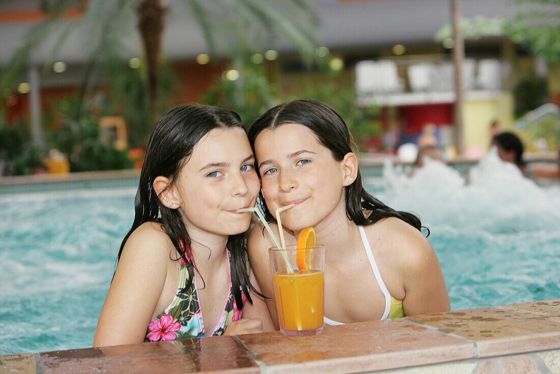 Zwei Mädchen in einem Schwimmbecken trinken Saft, Bad Waltersdorf, Steiermark, Österreich