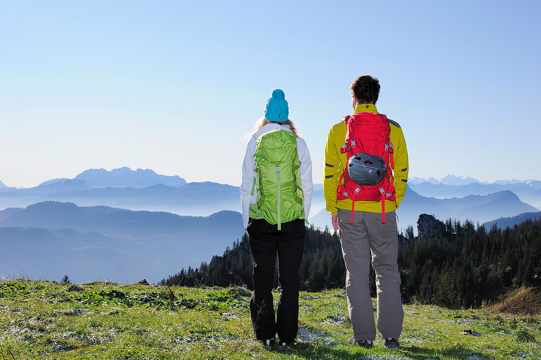 Junge Frau und junger Mann genießen die Aussicht auf das Kaisergebirge, Kampenwand, Chiemgauer Alpen, Chiemgau, Oberbayern, Bayern, Deutschland
