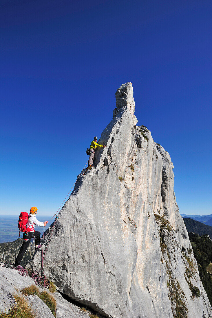 Young woman belaying climber at pinnacle, Kampenwand, Chiemgau Alps, Chiemgau, Upper Bavaria, Bavaria, Germany