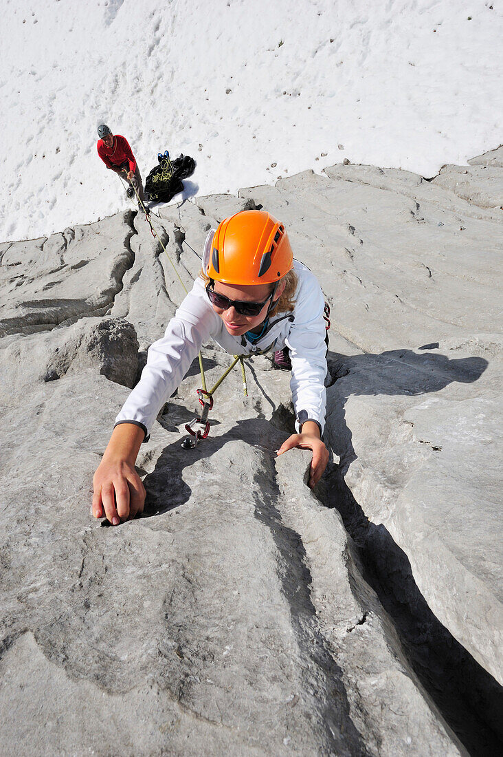 Young woman climbing while young man belaying, Multerkarwand, Treffauer, Wegscheidalm, Wilder Kaiser, Kaiser Mountain Range, Tyrol, Austria