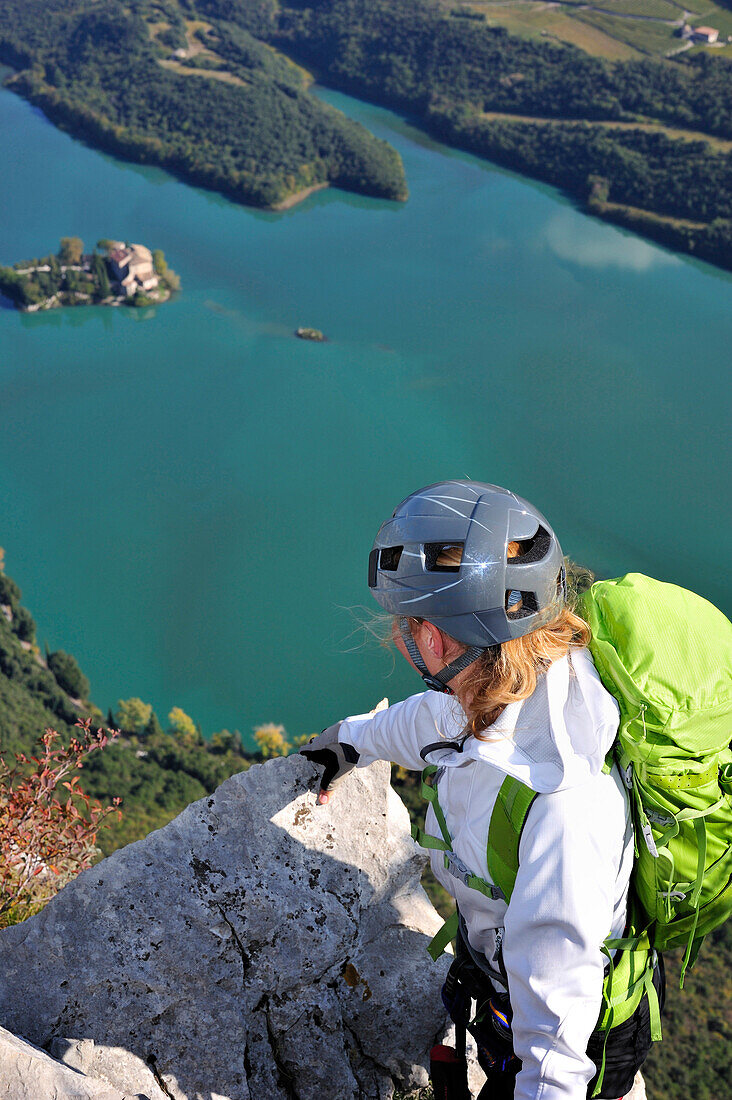 Young woman at fixed rope route Rino Pisetta looking to Lago die Toblino, Sarche, Calavino, Trentino, Trentino-Alto Adige, Suedtirol, Italy