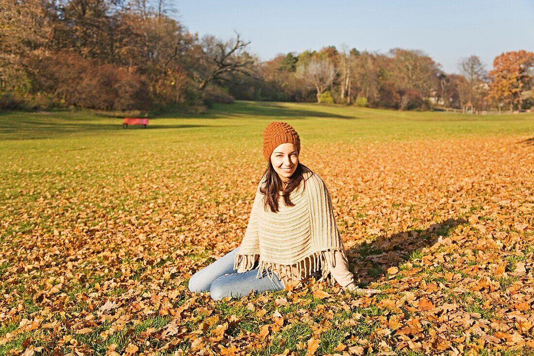 Portrait of a brunette woman sitting in the park in Autumn