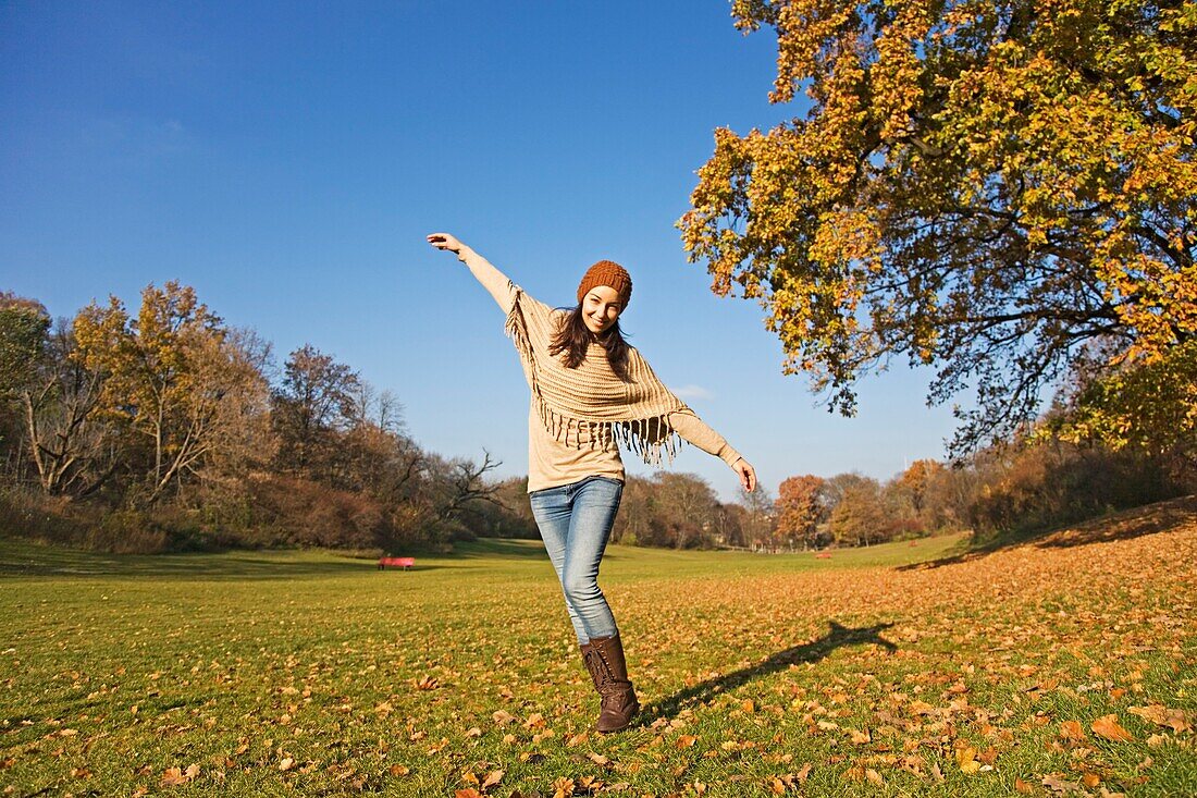 Portrait of a brunette woman in park in Autumn with arms opened