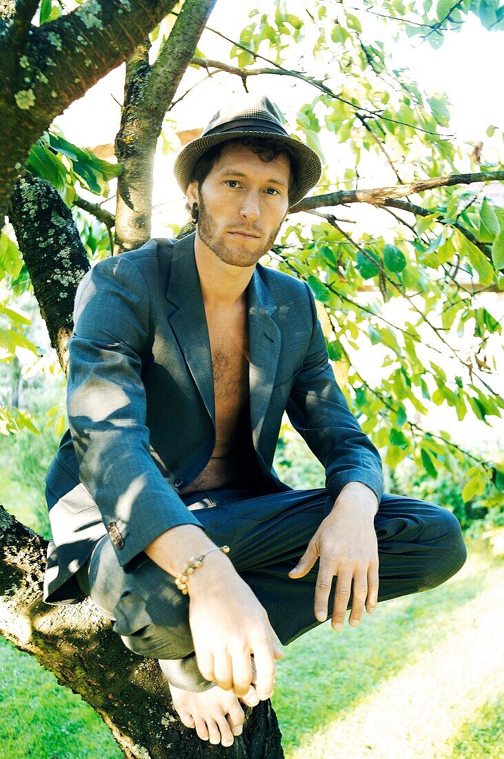 Hipster Man sitting in suit in a tree