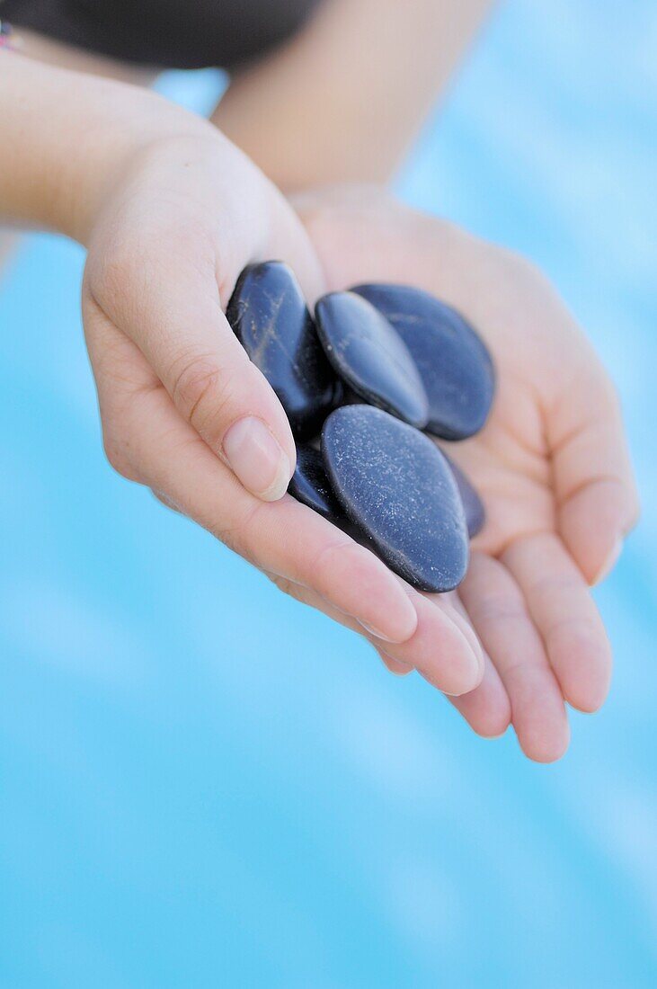 Close-up of a woman's hand holding zen's black stones