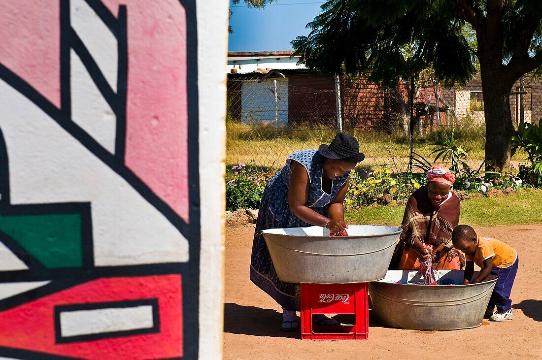 Africa, South Africa, Mpumalanga Province, KwaNdebele, Ndebele tribe, Mabhoko village, house of the artist Francina Mbonani, her daughters Bleji and Letty washing clothes helped by the young Sanelisiwe