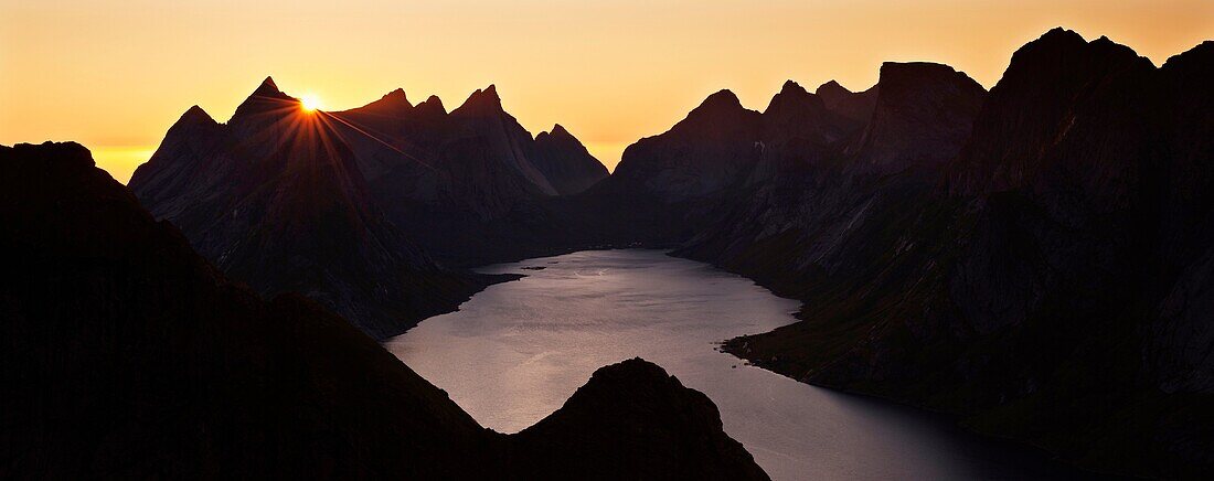 Sunset behind rugged mountain peaks and Kjerkfjord from Reinebringen peak, Reine, Lofoten islands, Norway