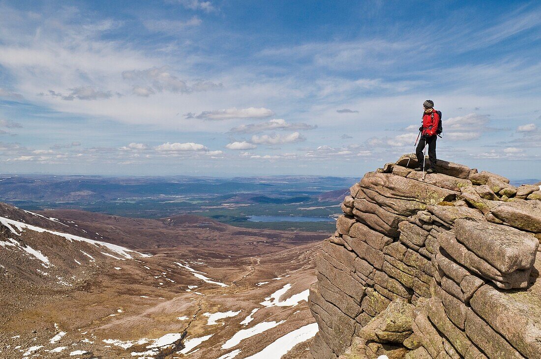 Female hiker stands on cliff near Cairn Gorm in the Cairngorm mountains of Scotland