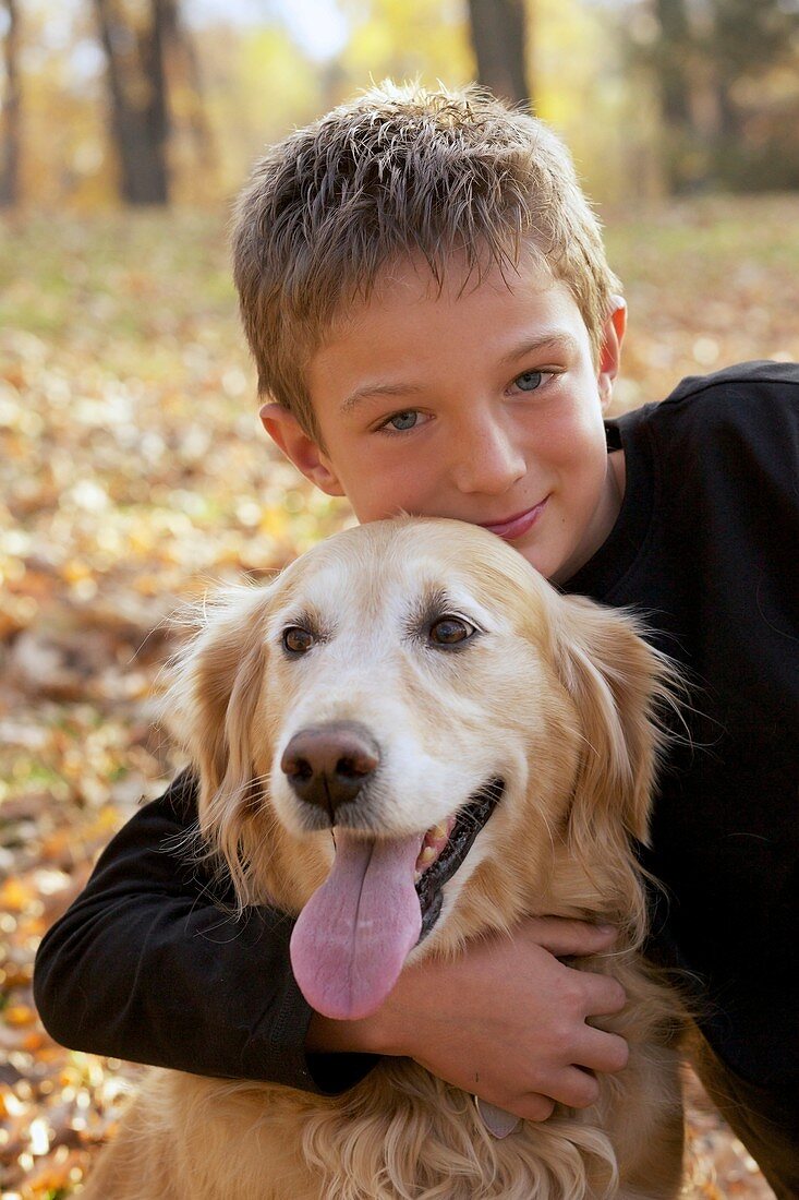 Portrait of happy young boy hugging his golden retriever dog