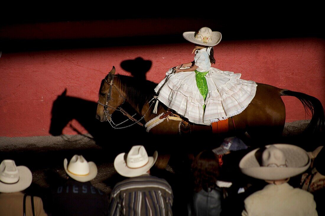 Spectators watch a Mexican amazona ride her horse at the National Charro Championship in Pachuca, Hidalgo State, Mexico. Escaramuzas are similar to US rodeos, where female competitors called ´Amazonas´ wear long skirts, and ride side saddle Male rodeo com