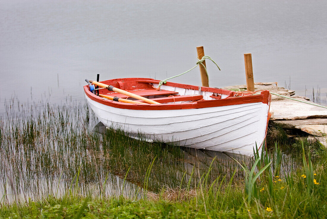 A traditional wooden boat beached by a small jetty by water on the Orkney Islands., Orkney Islands, Scotland
