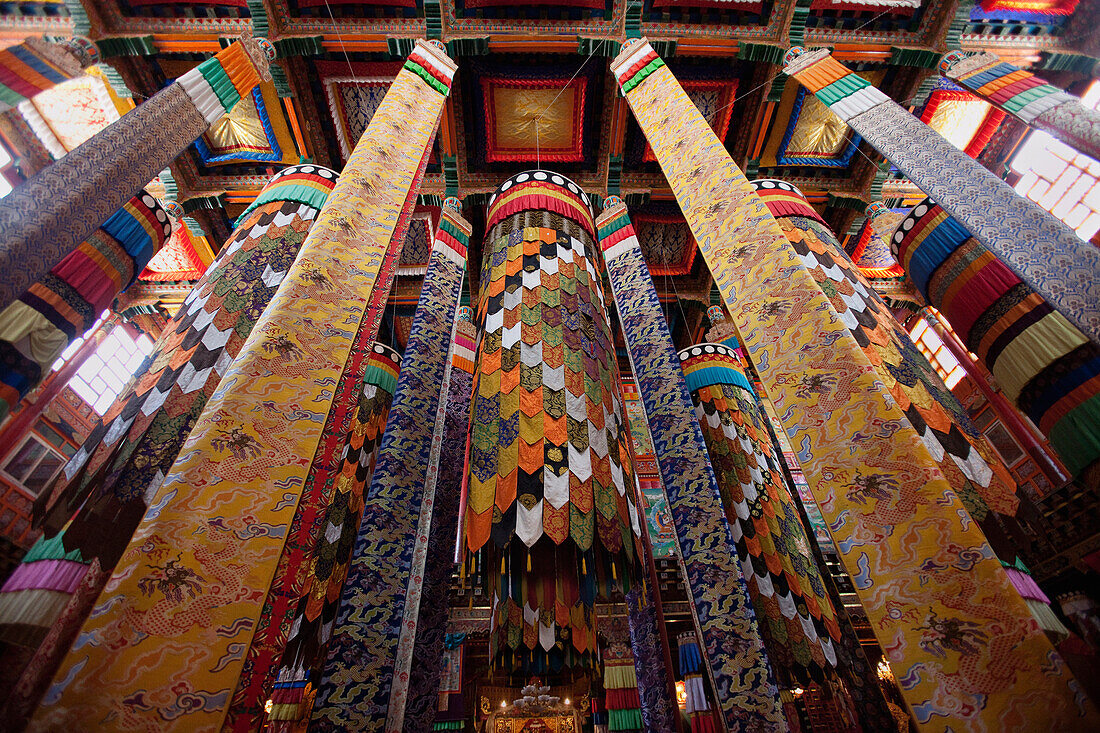 Derge Gonchen Gompa. The Sakya Monastery, being refurbished and rebuilt. Richly decorated pillars and fabric banners. Prayer Hall., Sichuan Tibet