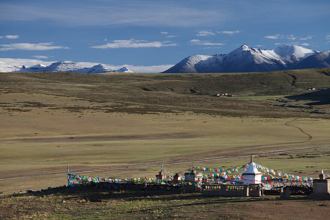 View of Mount Kailash from Chiu Monastery. Snowcapped mountains on the horizon. A temple with white stupa tower, with prayer flags. Buddhist temple., Mount Kailash, Tibet Autonomous Region