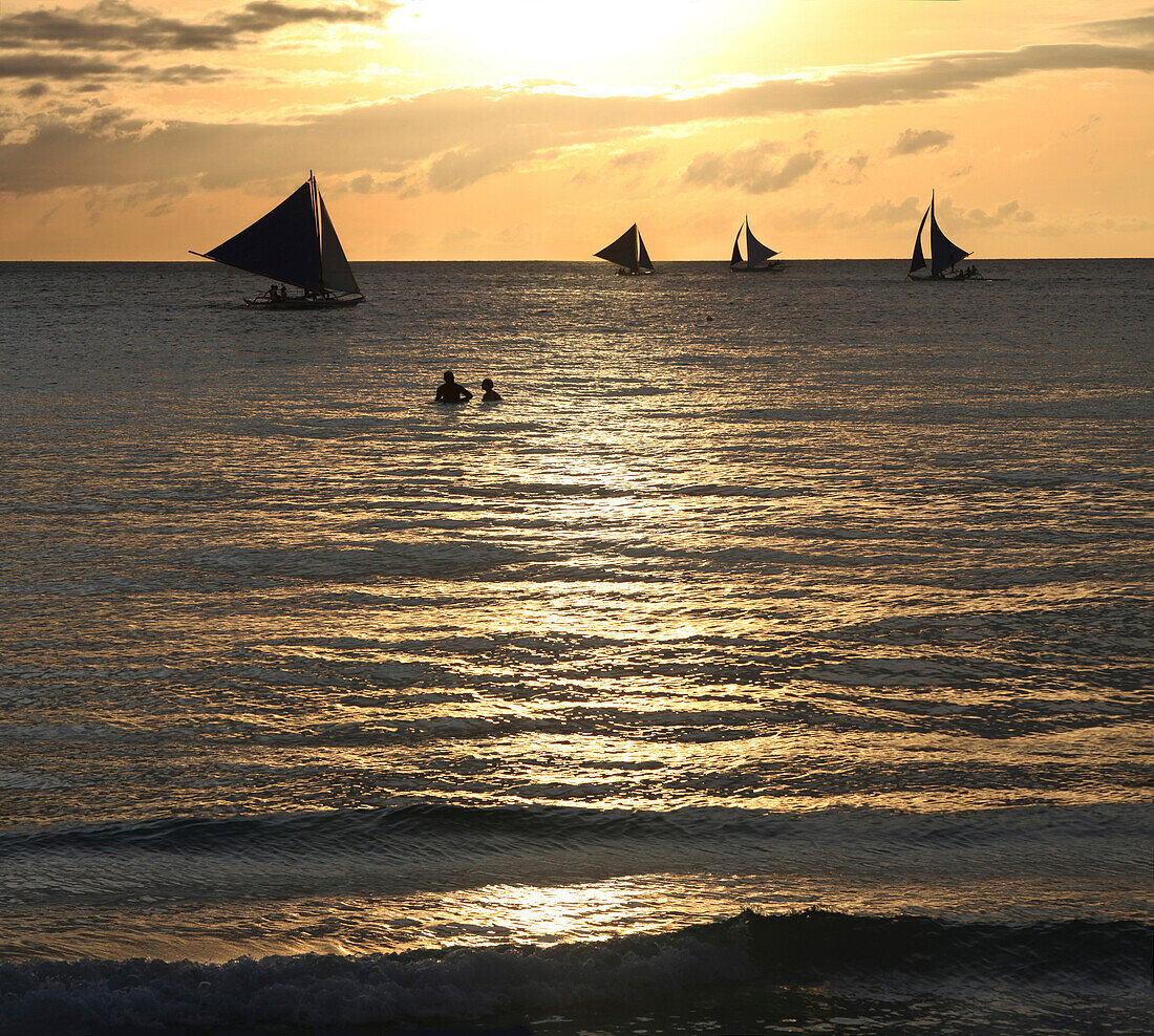 Badende und Segelboote im Meer bei Sonnenuntergang, Boracay, Philippinen, Asien