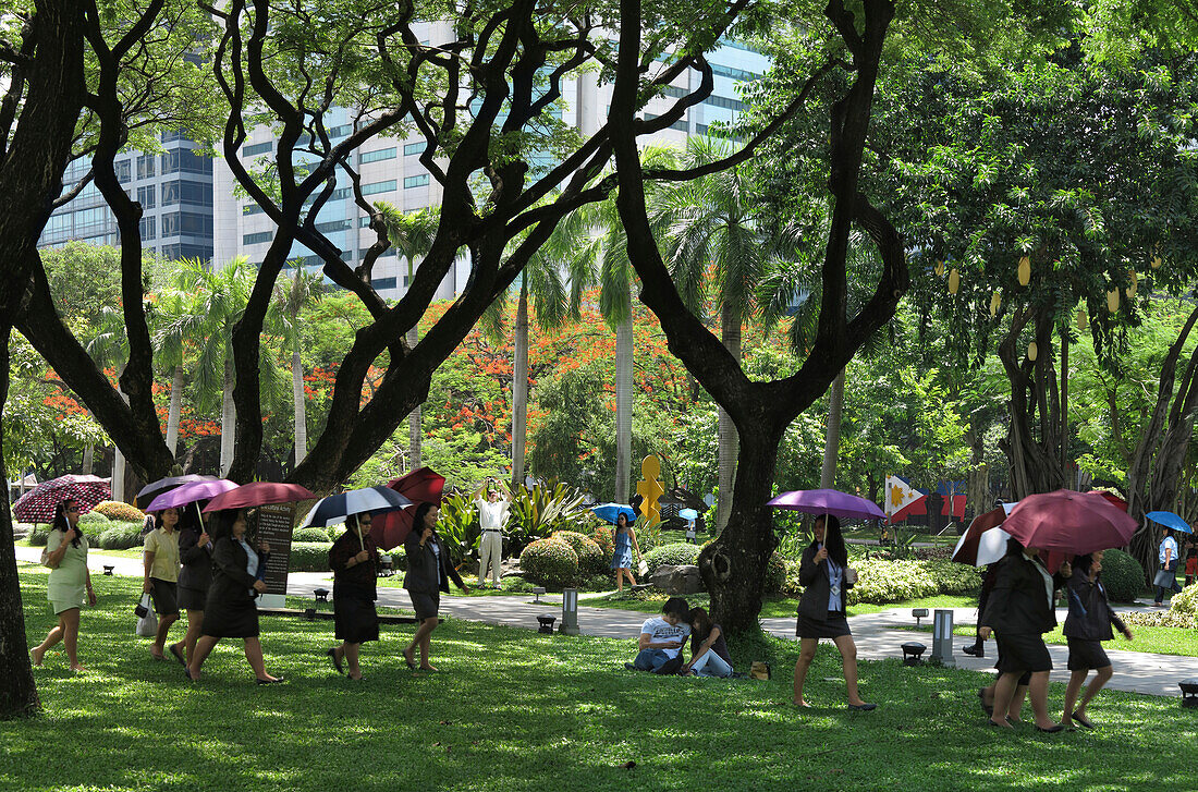 Frauen mit Regenschirmen im Ayala Triangle Park in Makati City, Luzon, Philippinen, Asien