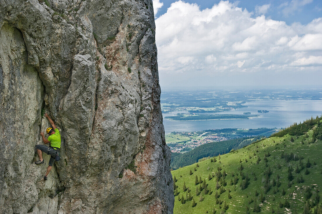 Rock climber ascending Kampenwand, Lake Chiemsee in the background, Chiemgau, Bavaria, Germany