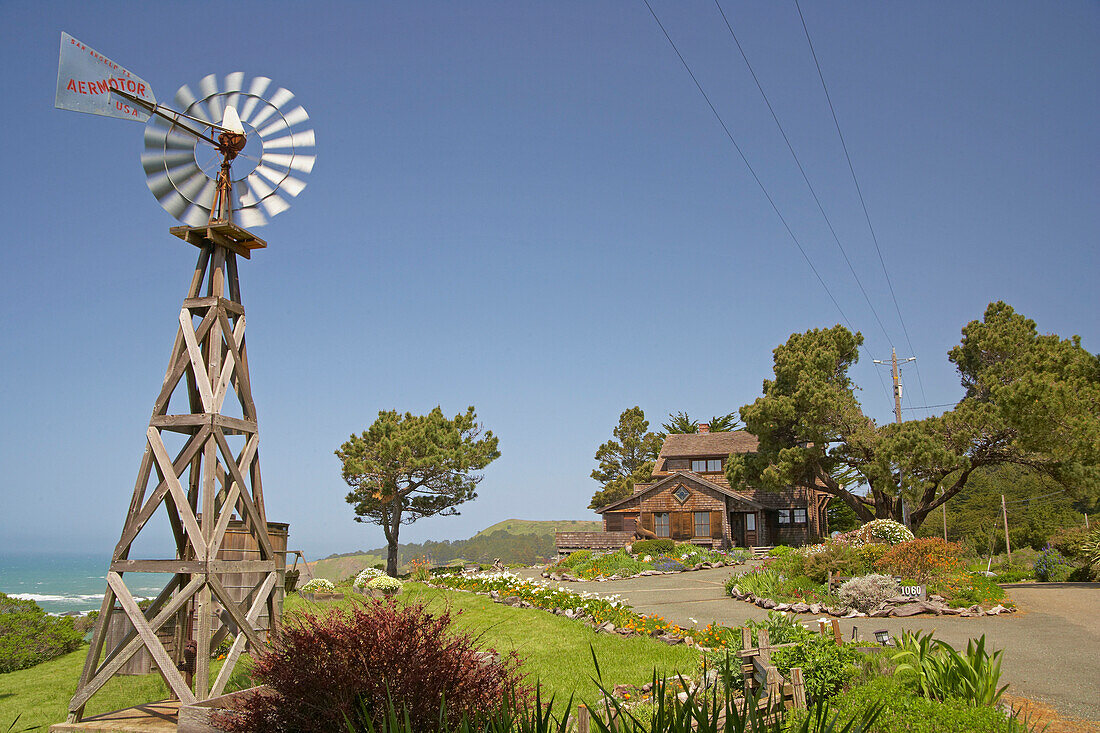 Westernmill in front of wooden house with garden at Navarro, Mendocino, California, USA, America